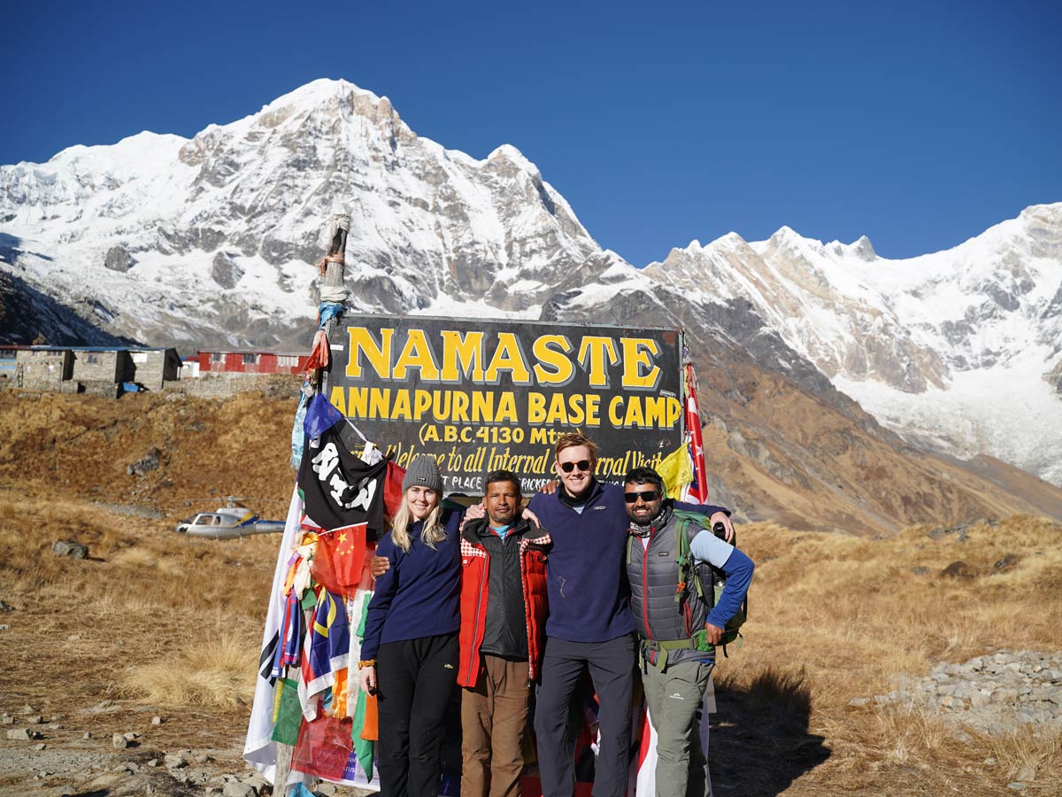 Group of joyful trekkers celebrating at Annapurna Base Camp, surrounded by breathtaking mountain scenery.