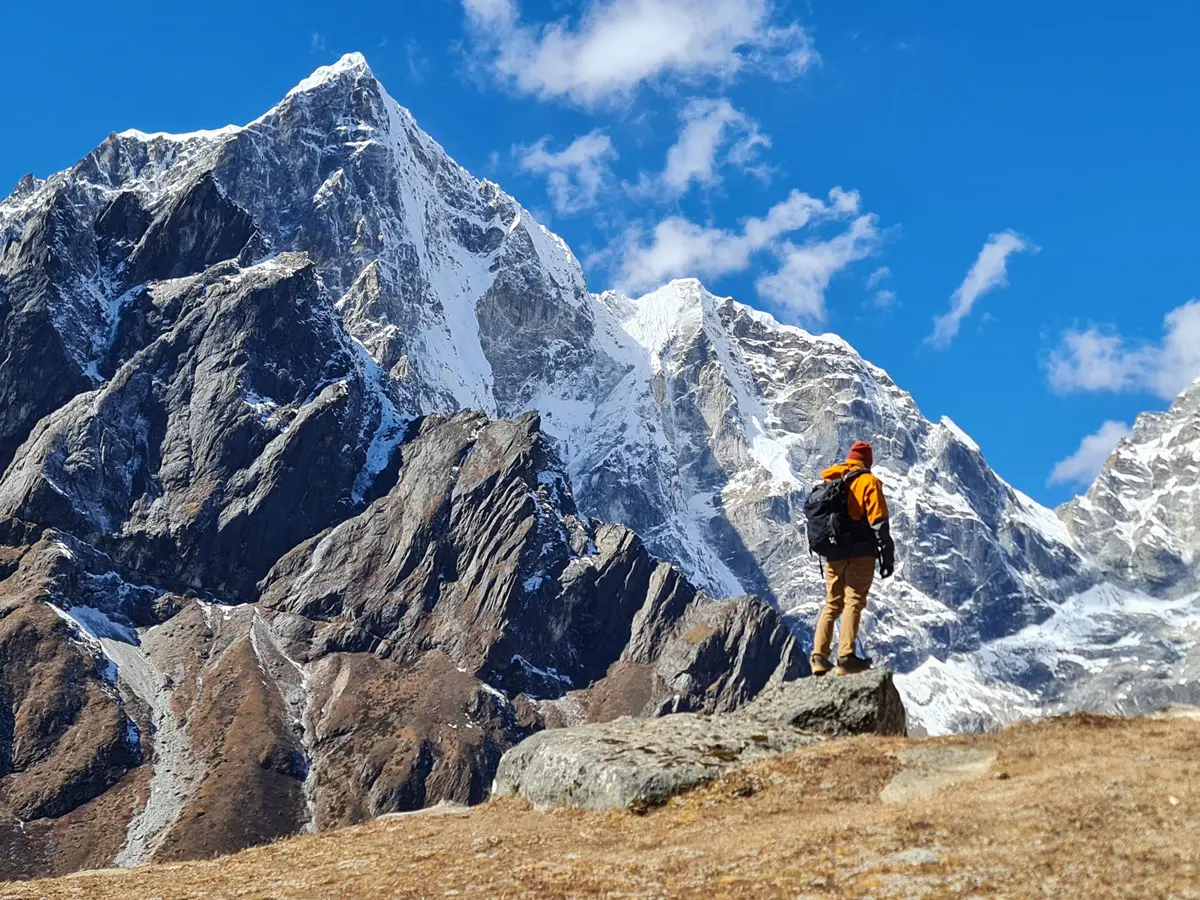 A trekker stands in awe before the towering Mount Taboche.